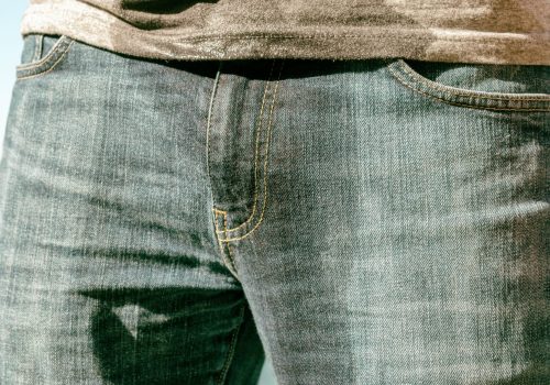 A man in wet jeans is standing on the beach